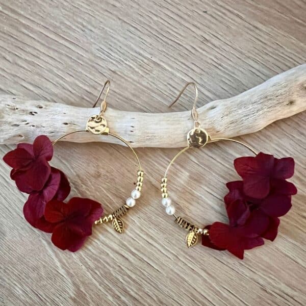 Les boucles Caroline dévoilent de véritables pétales d’hortensias couleur bordeaux stabilisés suspendus à des créoles dorées. Un bijou délicat et naturel.