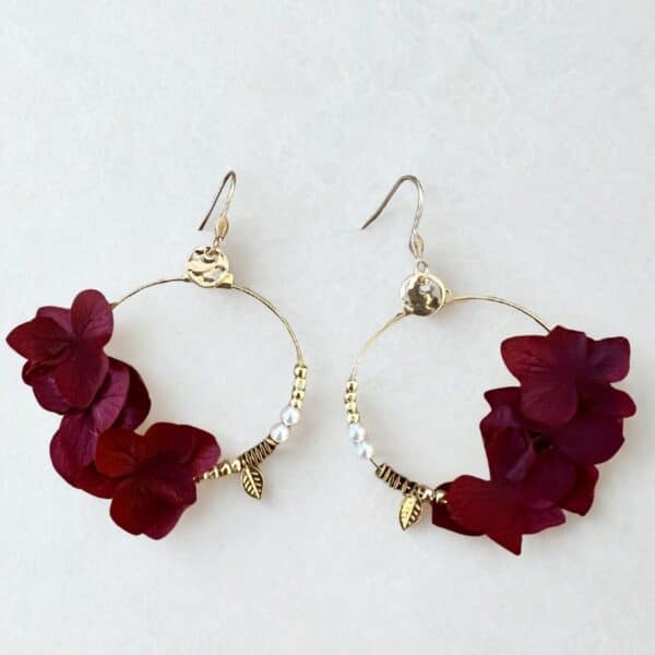 Les boucles Caroline dévoilent de véritables pétales d’hortensias couleur bordeaux stabilisés suspendus à des créoles dorées. Un bijou délicat et naturel.