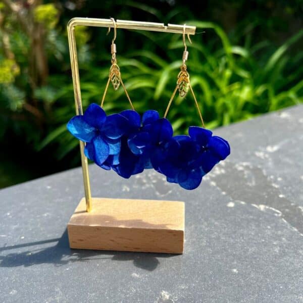 Boucles d’oreilles Chris en véritables hortensias bleu profond, délicatement montés en forme de goutte. Une pièce lumineuse et aérienne qui sublime chaque mouvement avec élégance naturelle.