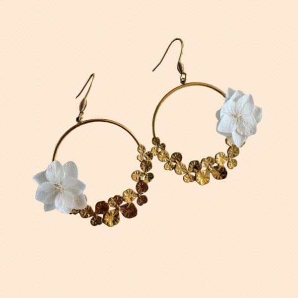 Les boucles d’oreilles Justine associent l’élégance d’un grand anneau doré à la délicatesse de petites fleurs blanches stabilisées. Un bijou floral raffiné et original, parfait pour une mariée ou pour illuminer une tenue avec une touche bohème chic.