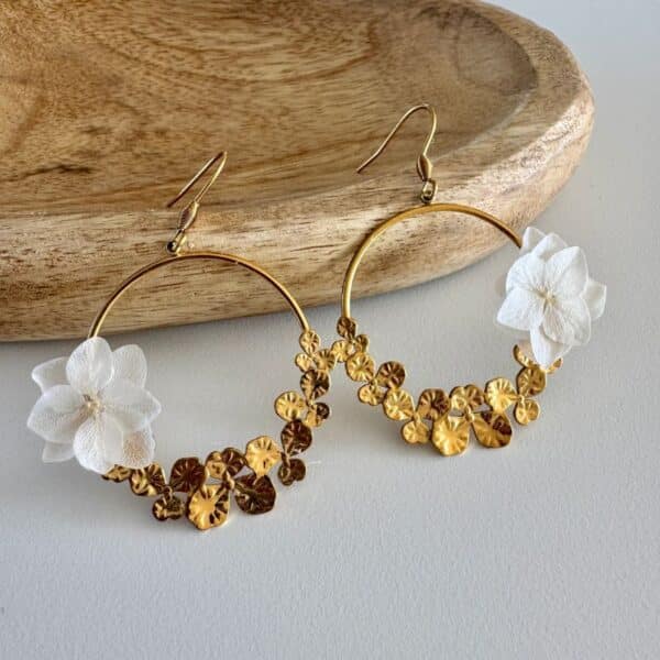 Les boucles d’oreilles Justine associent l’élégance d’un grand anneau doré à la délicatesse de petites fleurs blanches stabilisées. Un bijou floral raffiné et original, parfait pour une mariée ou pour illuminer une tenue avec une touche bohème chic.