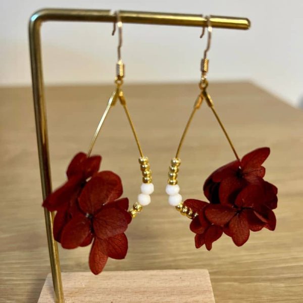 Les boucles Fanette dévoilent de véritables pétales d’hortensias couleur bordeaux stabilisés suspendus à des créoles en forme de gouttes dorées.